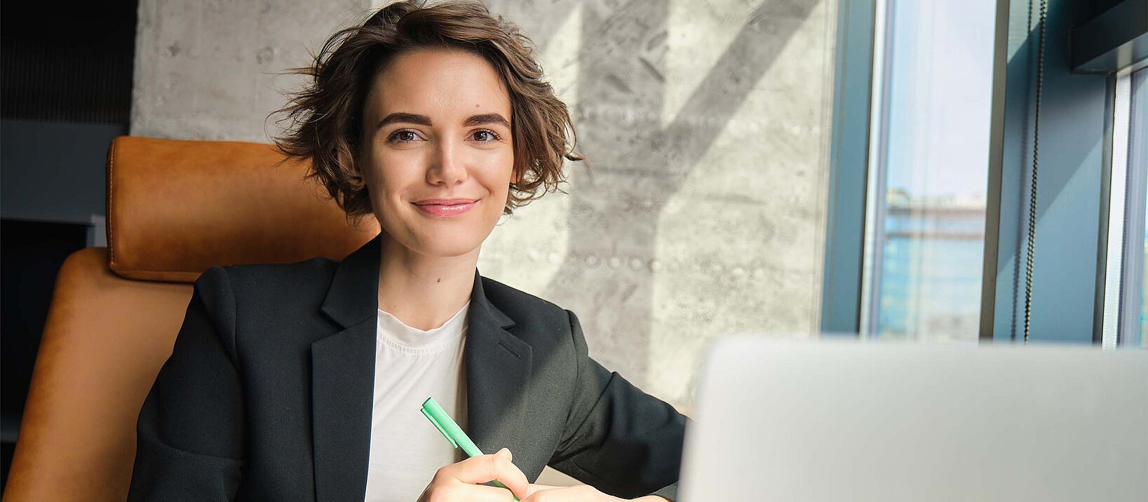 junge Frau im Anzug am Laptop