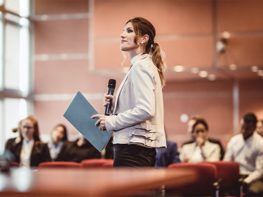 Frau mit Mikrofon vor Publikum