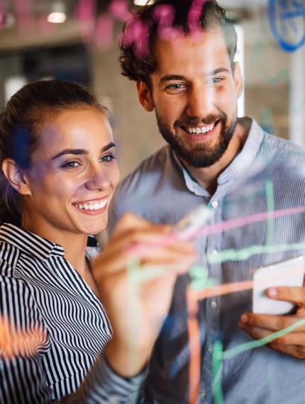 2 Personen entwickeln eine Idee an einer Tafel, Due persone sviluppano un'idea su una lavagna.